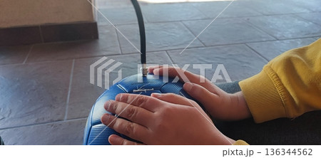 Closeup boy is pumping air into football. Concept, Portable sport equipment for inflating ball. Easy and convenient that kids can do themselves with a manual pump. Closeup boy is pumping air into football. Concept, Portable sport equipment for inflating ball. Easy and convenient that kids can do themselves with a manual pump. 136344562