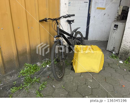 yellow backpack near the bike on the sidewalk. delivery concept 136345196