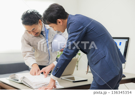 会社で資料を見ながら打ち合わせするエンジニア 会社で資料を見ながら打ち合わせするエンジニア 136345354