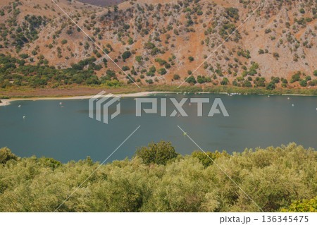 Hidden mountain lake with calm turquoise water red rocks and green trees. 136345475