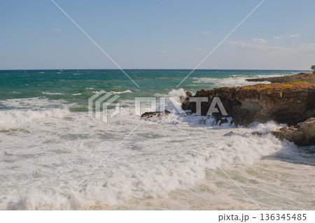 Furious storm and white foam turquoise waves crashing on rocky coast. 136345485
