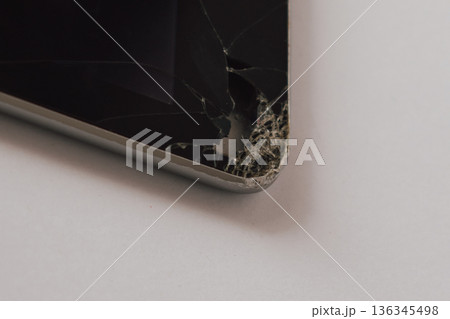 Close-up of a broken tablet display with cracks and visible damage to the device's interior 136345498