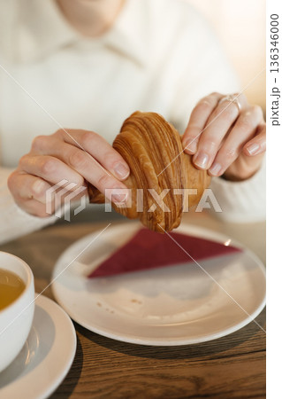 Enjoying a croissant with tea at a cozy cafe during morning hours 136346000