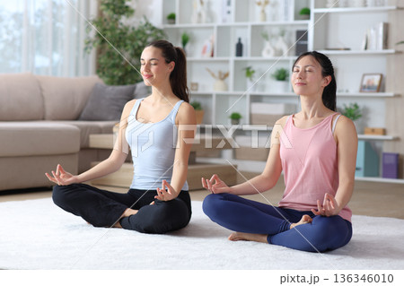 Diverse women doing yoga together at home 136346010