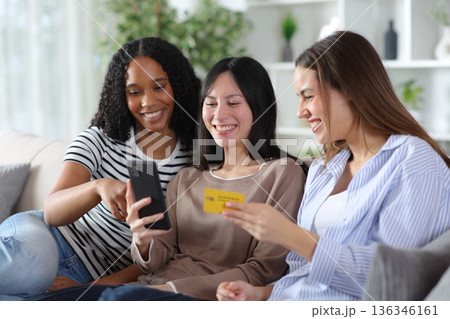 Three happy diverse friends buying online at home 136346161