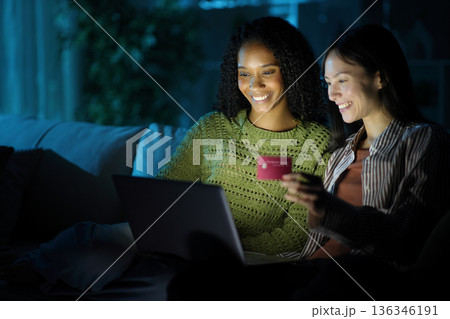 Happy diverse women buying online in the night at home 136346191