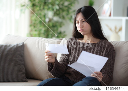 Frustrated asian woman reading letter at home 136346244