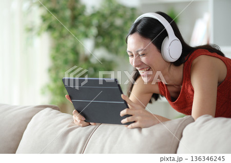 Funny asian woman watching online media and laughing Funny asian woman watching online media and laughing 136346245