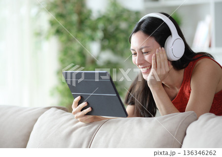 Happy asian woman watching streaming content at home Happy asian woman watching streaming content at home 136346262