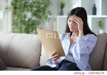 Worried asian woman checking documents at home 136346274