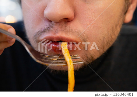 man eats fat pasta, sucks it with his mouth showcasing overeating and unhealthy eating habits. concept of obesity, diabetes, gluttony, diabetes, overeating, close-up of chewing mouth 136346401