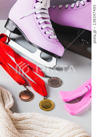 Figure skating skates, medals, covers and a scarf on a light background vertical view 136347493