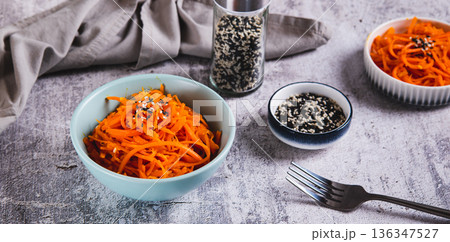 Korean carrots with sesame seeds in a bowl on the table web banner 136347527