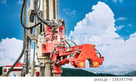 Drilling rig is active at a resource site conducting drilling for oil and gas. The weather is clear with clouds in the background during the day 136347740