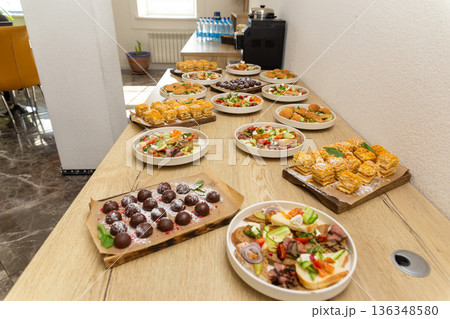 Assorted catering food with bruschetta, slider, and pastry on a wooden counter 136348580