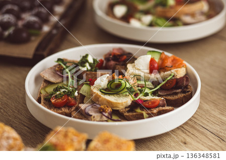 Assorted catering bruschetta with salmon, meat, and vegetables on a white plate. Assorted catering bruschetta with salmon, meat, and vegetables on a white plate. 136348581