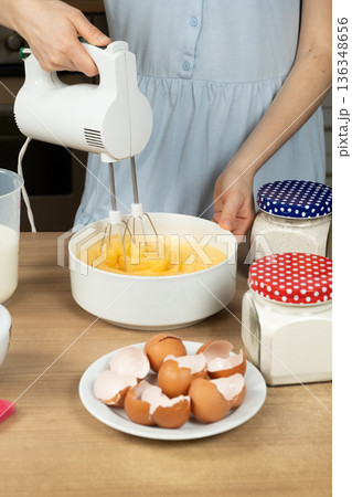 Woman Using an Electric Hand Mixer to Whip Eggs for Waffle or Cake Batter. Woman Using an Electric Hand Mixer to Whip Eggs for Waffle or Cake Batter. 136348656