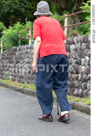 屋外で杖を使って歩くシニア女性の後ろ姿 全身 高齢者イメージ 136348955