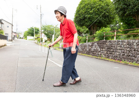 屋外で杖を使って道路を歩くシニア女性 全身 136348960