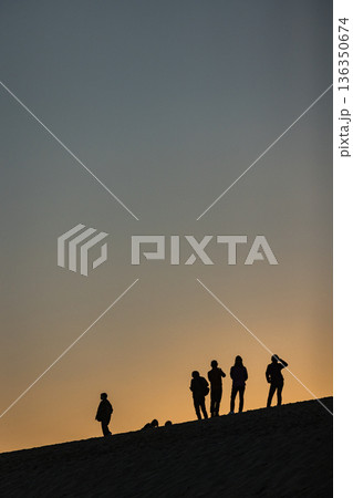 日本　鳥取県鳥取市福部町にある鳥取砂丘の馬の背にのる人々のシルエットと夕焼け空 136350674