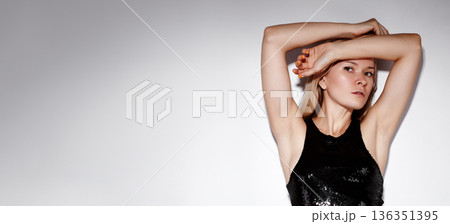 Beauty Fashion Woman Posing Arms Raised, Black Sequin Dress, Confident Performance Vibe, Strong Posture, Directional Lighting, Minimalist White Background, Edgy Editorial Styling, Expressive 136351395