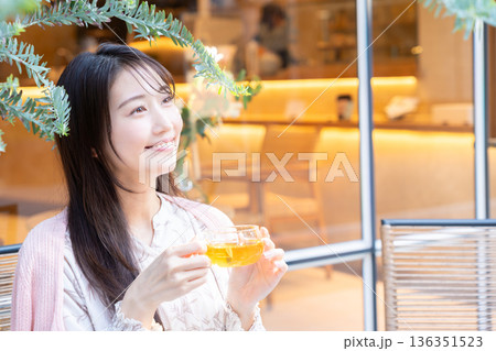 カフェのテラス席で紅茶を飲む若い女性 136351523