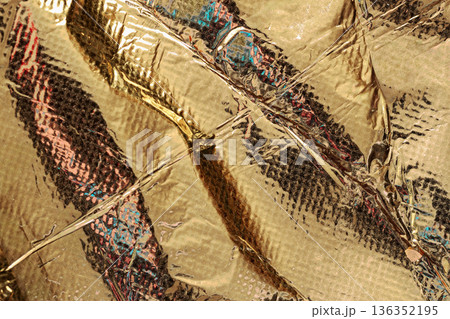 Gold foil abstract texture. Crinkled shiny gold foil surface with abstract reflections and light distortions, layered metallic pattern. Natural background for design 136352195