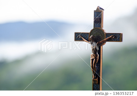 Close up view of a weathered wooden holy cross centered against a blurred landscape symbolizing devotion belief resilience and quiet spiritual strength. 136353217