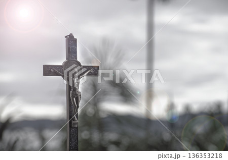 Dark silhouetted holy cross photographed in monochrome tones with dramatic sky creating a moody atmosphere of faith sacrifice and solemn remembrance. 136353218