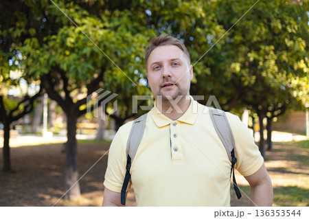Man in Yellow Shirt Standing Outdoors in Green Park with Trees on Sunny Day 136353544