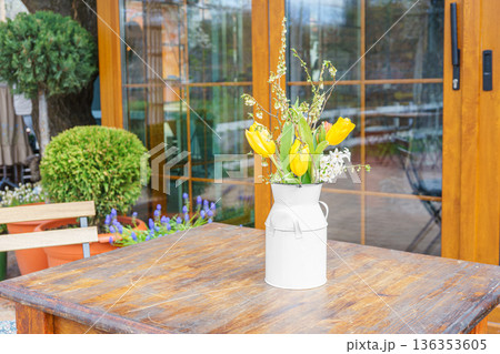 Spring bouquet of yellow tulips and white flowers in rustic metal vase on wooden table outdoors Spring bouquet of yellow tulips and white flowers in rustic metal vase on wooden table outdoors 136353605