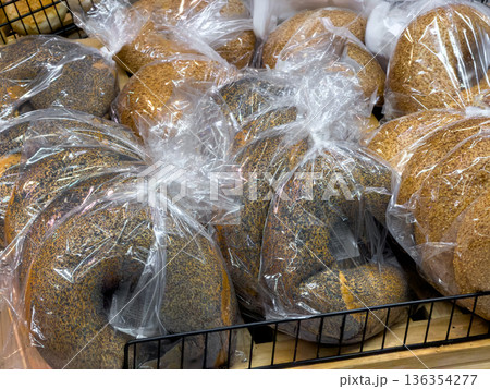 Freshly baked poppy seed and sesame bagels individually packaged in clear plastic bags, ready for convenient retail sale in a grocery store bakery Freshly baked poppy seed and sesame bagels individually packaged in clear plastic bags, ready for convenient retail sale in a grocery store bakery 136354277