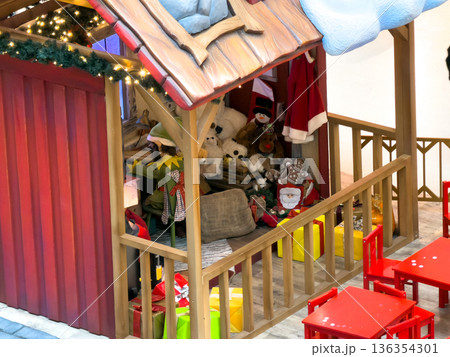 Charming Christmas workshop display in a shopping mall, featuring an elf, wrapped gifts, and festive holiday decorations, creating a magical atmosphere for children Charming Christmas workshop display in a shopping mall, featuring an elf, wrapped gifts, and festive holiday decorations, creating a magical atmosphere for children 136354301