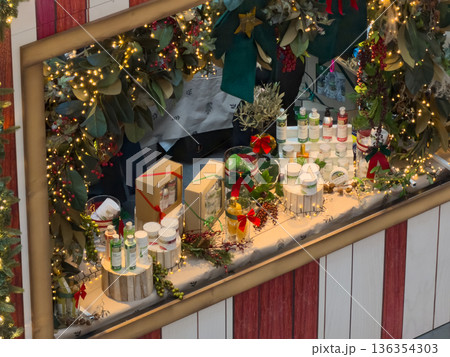 Festive retail display of natural cosmetic and personal care products beautifully decorated with Christmas lights, green foliage, and red berries for holiday shopping Festive retail display of natural cosmetic and personal care products beautifully decorated with Christmas lights, green foliage, and red berries for holiday shopping 136354303