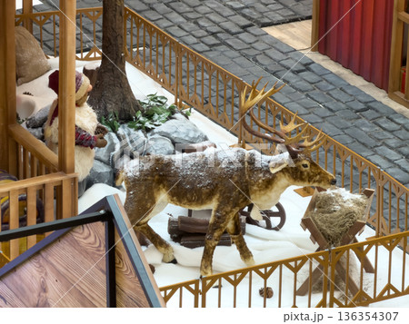 Festive reindeer and elf figures in a snowy village scene, creating a charming winter holiday display perfect for seasonal marketing and celebrations Festive reindeer and elf figures in a snowy village scene, creating a charming winter holiday display perfect for seasonal marketing and celebrations 136354307