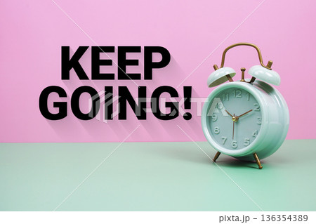 Black alarm clock on a pastel green and pink background with the text "Keep Going" 136354389