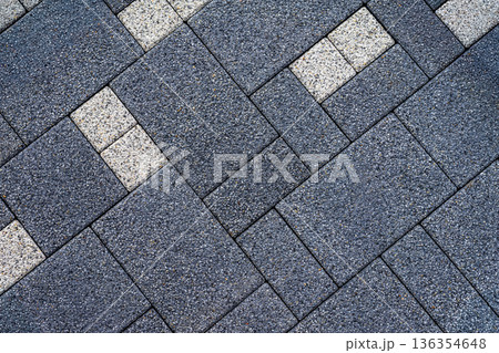 Dark gray paving tiles with speckled gravel texture and diagonal layout, accented by light tiles. Concept of paving tiles, textured surfaces, modern design background 136354648
