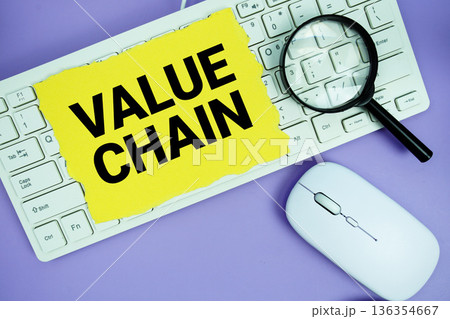 Yellow torn paper with the text "Value Chain" placed on a white keyboard, and magnifying glass and a computer mouse Yellow torn paper with the text "Value Chain" placed on a white keyboard, and magnifying glass and a computer mouse 136354667