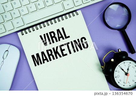 Notepad with the text "Viral Marketing" and white keyboard, wireless mouse, magnifying glass and alarm clock 136354670