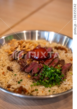 Beef with garlic fried rice, a dish of rice topped with rare beef served with pickled egg yolk with fish sauce on a pan 136355142
