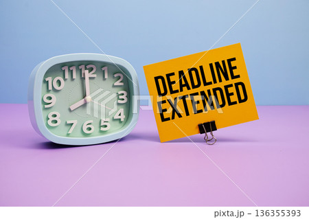 Deadline Extended text and alarm clock on blue and purple background 136355393