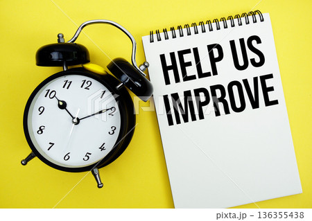 Help Us Improve text with alarm clock flat lay on yellow background 136355438