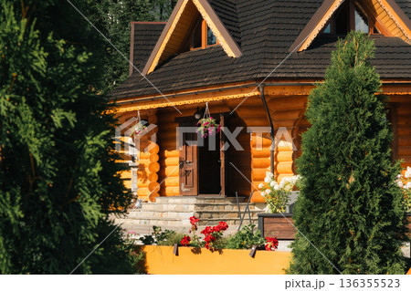 Traditional wooden log house with flowers and open door in mountain village 136355523