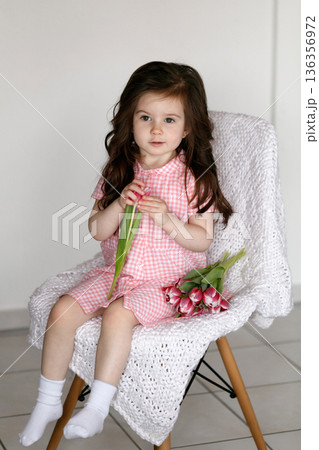 Little girl with pink tulips indoors Little girl with pink tulips indoors 136356972