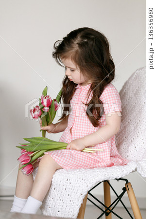 Little girl with bouquet of pink tulips Little girl with bouquet of pink tulips 136356980