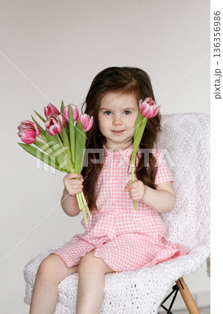 Little girl with pink tulips indoors 136356986
