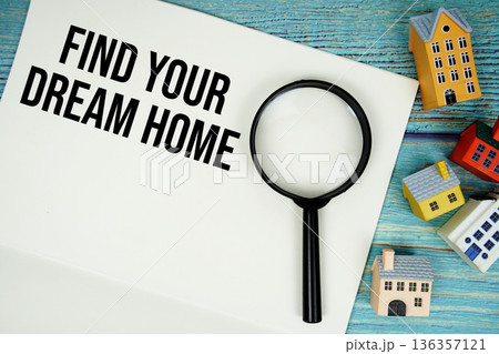 Notepad with "Find Your Dream Home" with magnifying glass and house model on wooden background 136357121