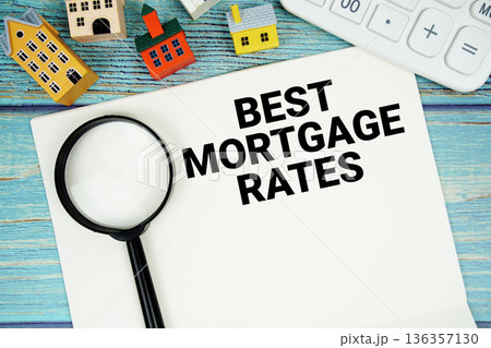 Notepad with "Best Mortgage Rates" with Calculator, magnifying glass and house model on wooden background 136357130