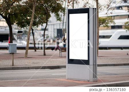 Blank vertical outdoor digital advertising screen mockup on a city street pavement, offering copy space for urban marketing campaigns and public information displays 136357180