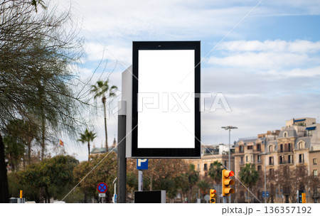 Blank vertical billboard on urban street offers clean white copy space for branding, promotions or marketing messages, set against buildings, bare and palm trees under cloudy sky Blank vertical billboard on urban street offers clean white copy space for branding, promotions or marketing messages, set against buildings, bare and palm trees under cloudy sky 136357192